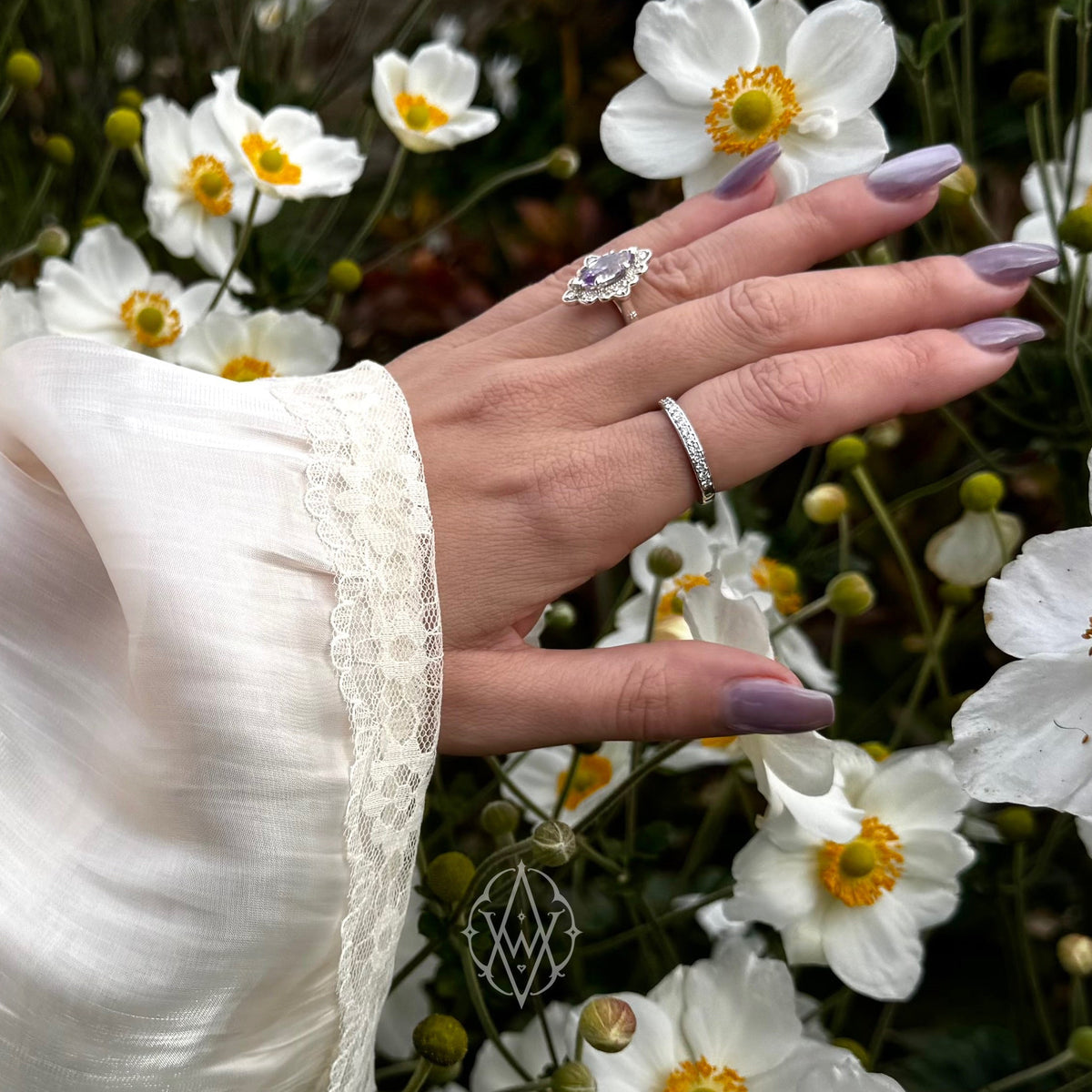 Ashlen, woman’s hand, extended with 2 rings visible. White dress covers arm to hand. White flowers in background.

Photo taken in Roche Harbor by Kyle Ketcham